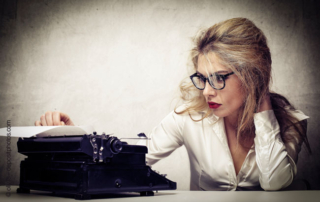 Perfektionismus bedeutet, sein Werk zu liebe - Frau mit kritischem Blick auf Schreibmaschine